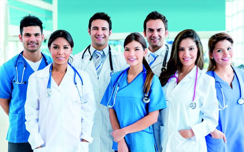 Doctors and nurses in white coats and blue scrubs standing together