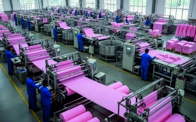 A large production floor with workers operating fabric rolling machines