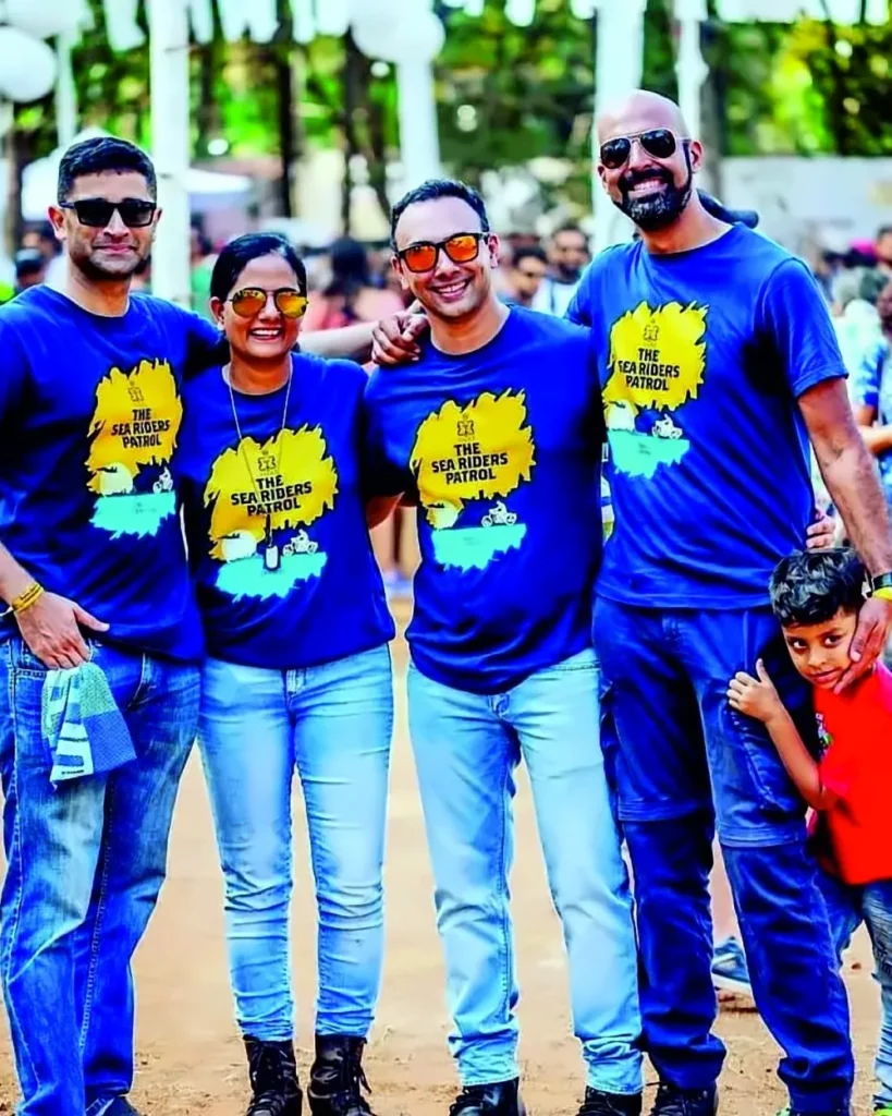 Four adults at an outdoor event wearing matching blue printed T-shirts