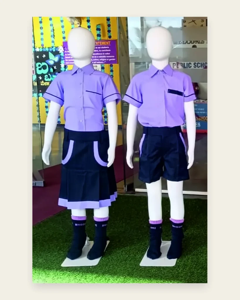 Two child mannequins in lavender shirts, one with a navy pleated skirt and one with navy shorts