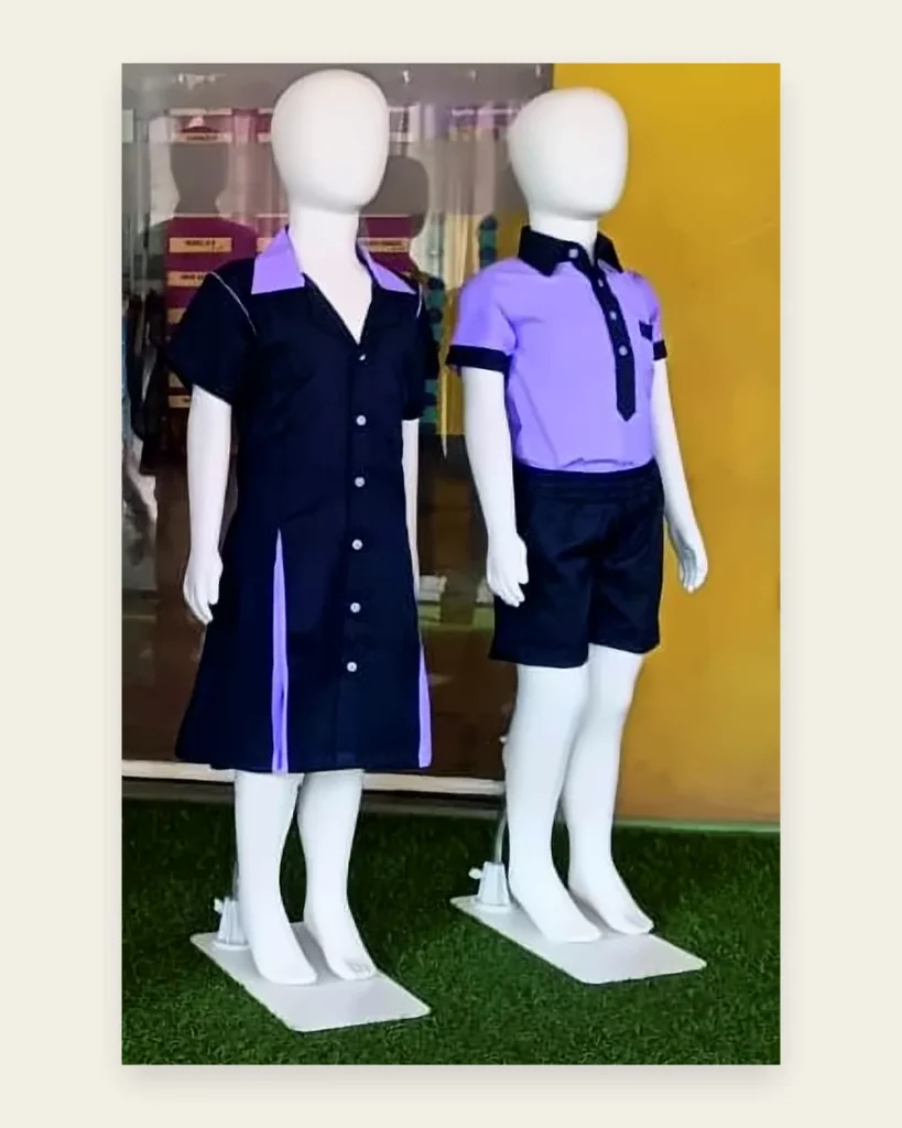 Child mannequins in a navy pinafore dress with lavender panels and a lavender shirt with navy shorts